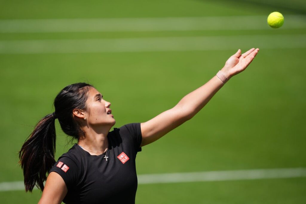 Emma Raducanu wearing tennis gear while looking concerned on a grass court