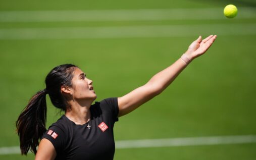 Emma Raducanu wearing tennis gear while looking concerned on a grass court