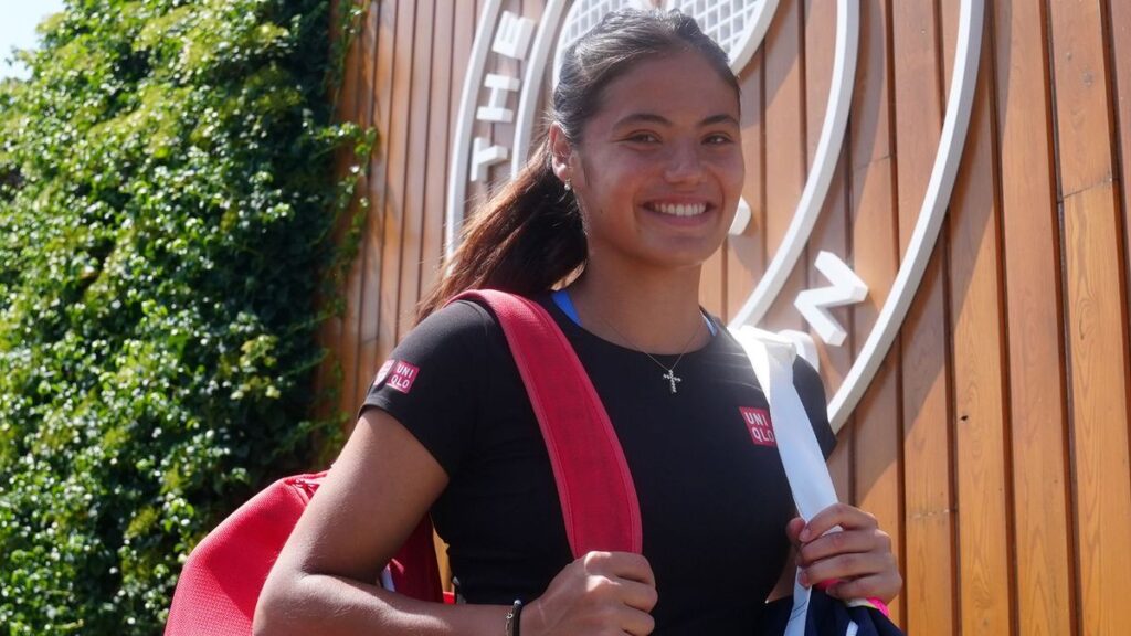 Emma Raducanu smiling and celebrating a point on a grass tennis court