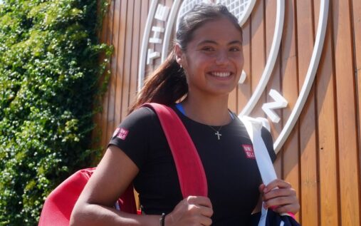 Emma Raducanu smiling and celebrating a point on a grass tennis court