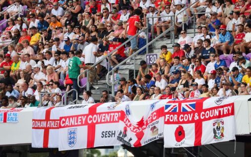 England football fans waving flags and cheering in the stands during an international match
