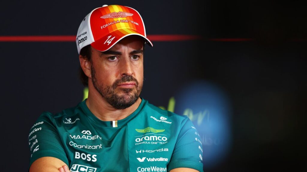 Fernando Alonso walking through the Formula 1 paddock wearing his green Aston Martin team apparel