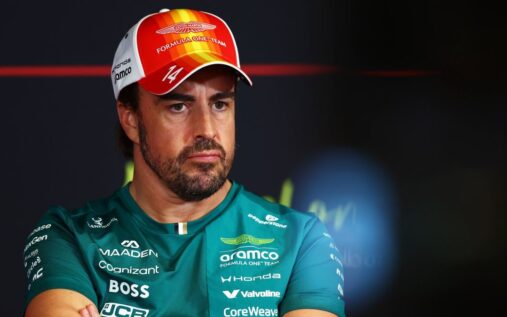 Fernando Alonso walking through the Formula 1 paddock wearing his green Aston Martin team apparel