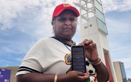 Frustrated football fans standing outside a World Cup stadium looking at their mobile phones