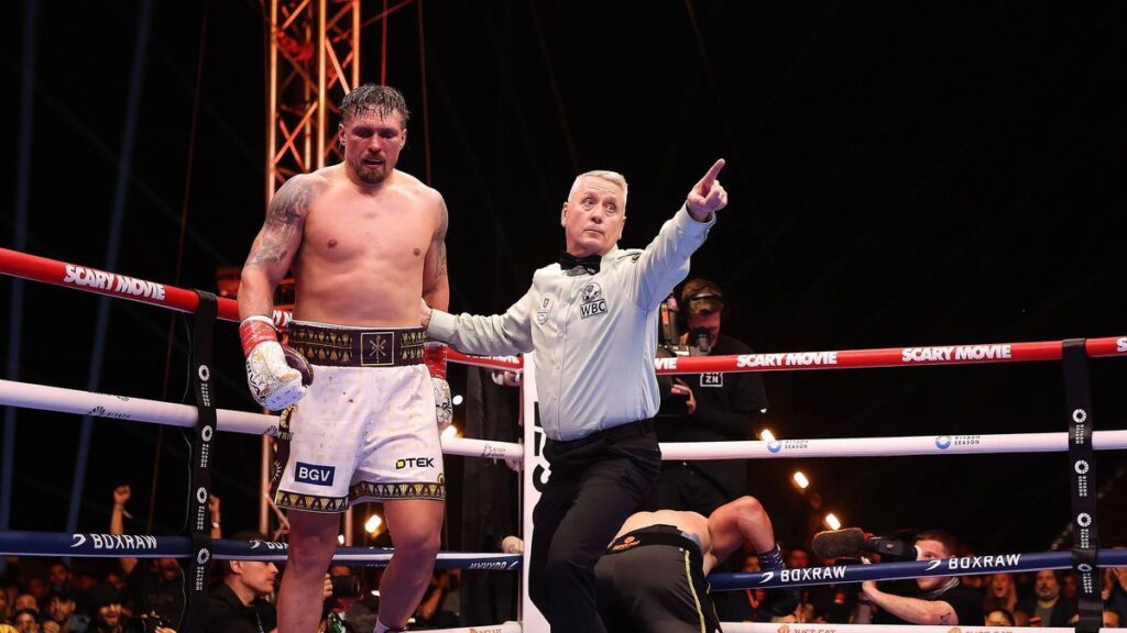 Oleksandr Usyk holding his heavyweight boxing world championship belts in the ring
