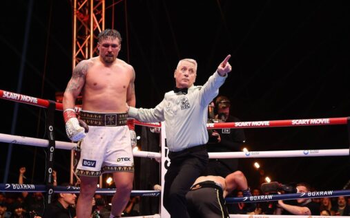 Oleksandr Usyk holding his heavyweight boxing world championship belts in the ring