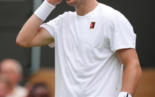Jack Draper preparing to hit a tennis ball on a grass court