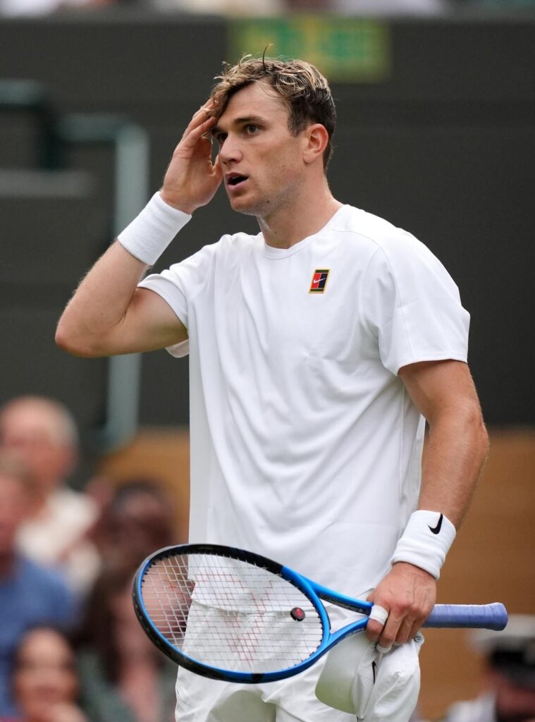 Jack Draper preparing to hit a tennis ball on a grass court