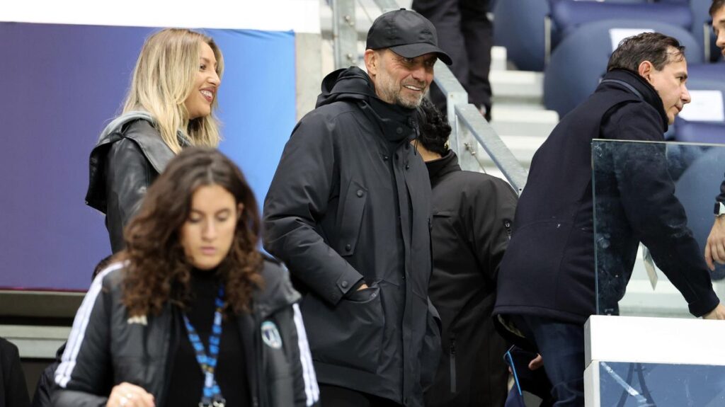 Jurgen Klopp smiling on the touchline while wearing his trademark glasses