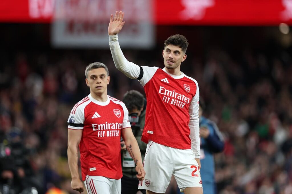 Kai Havertz wearing an Arsenal kit pointing to the club badge on his chest.