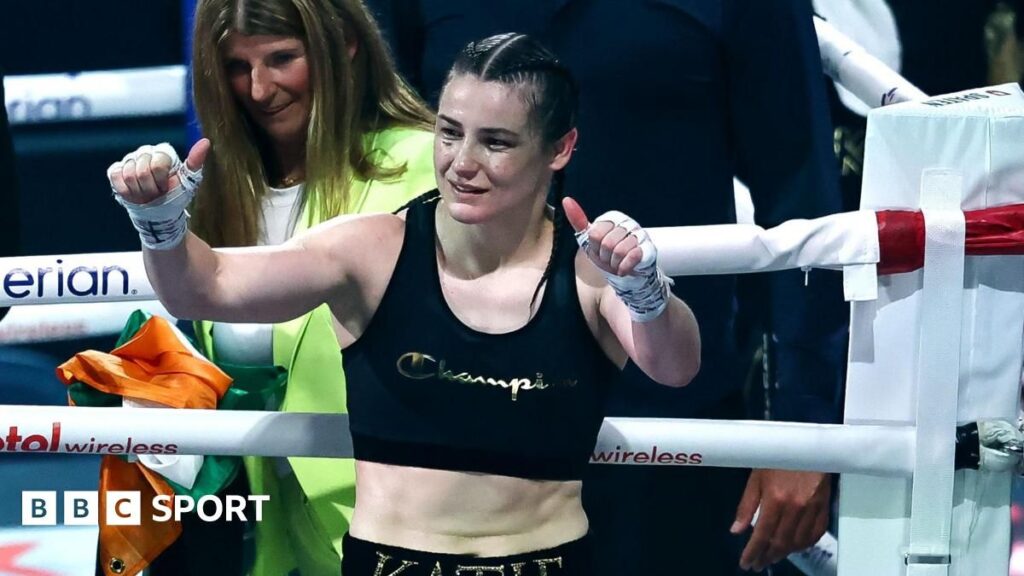 Katie Taylor wearing boxing gloves and holding her undisputed world championship belts