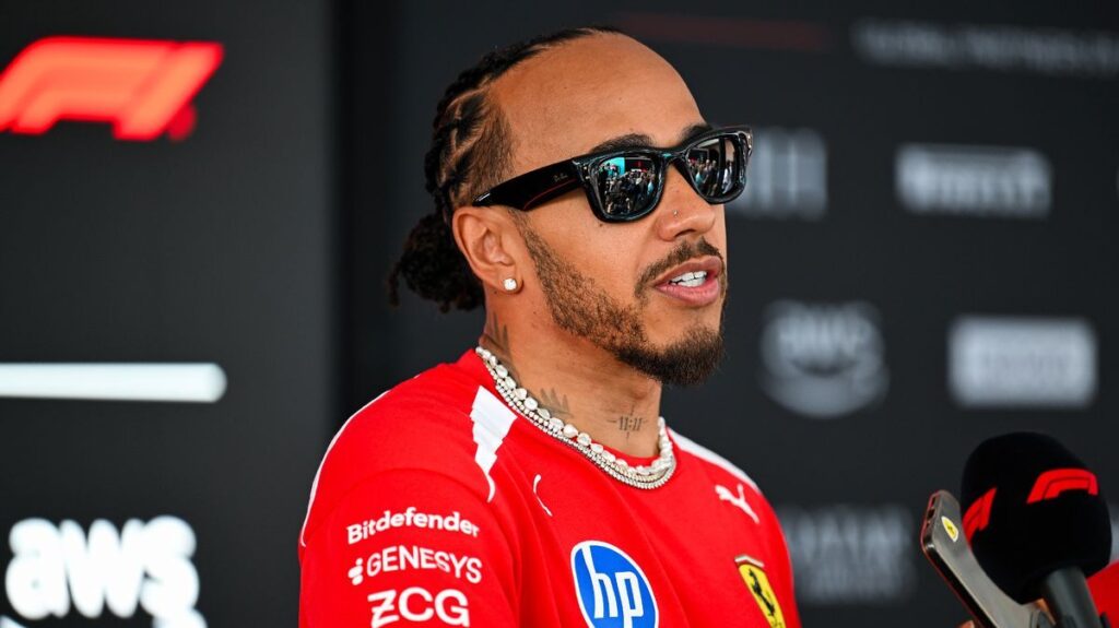 Lewis Hamilton walking through the Formula 1 paddock wearing his red Ferrari race suit