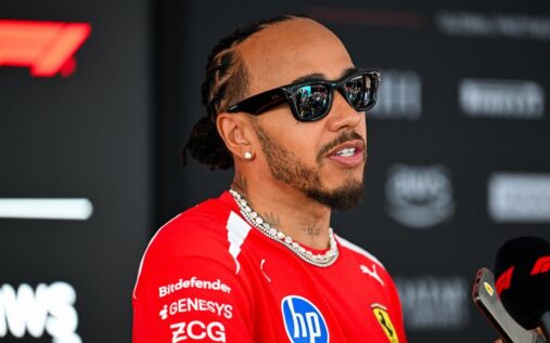 Lewis Hamilton walking through the Formula 1 paddock wearing his red Ferrari race suit
