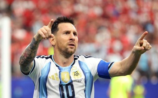 Lionel Messi wearing the Argentina captain's armband looking thoughtful on the pitch