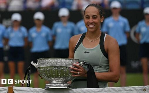 Madison Keys smiling while holding the Eastbourne International winner's trophy on a grass court