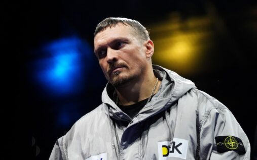 Oleksandr Usyk holding his unified heavyweight championship belts aloft in the boxing ring