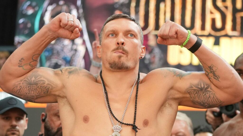 Oleksandr Usyk holding his world heavyweight championship belts in the ring