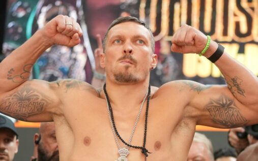 Oleksandr Usyk holding his world heavyweight championship belts in the ring