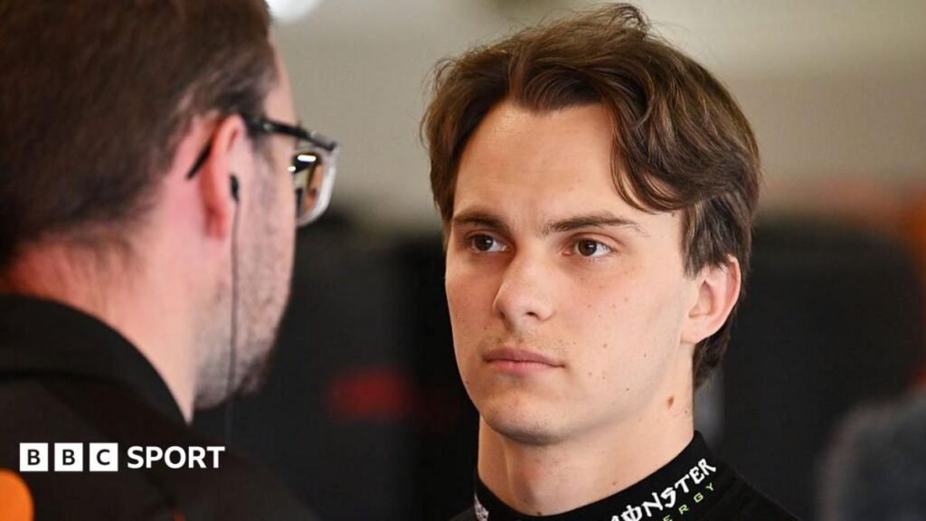 Oscar Piastri wearing his McLaren race suit and helmet looking frustrated at the Monaco Grand Prix