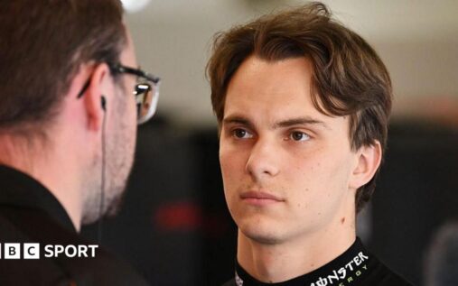Oscar Piastri wearing his McLaren race suit and helmet looking frustrated at the Monaco Grand Prix
