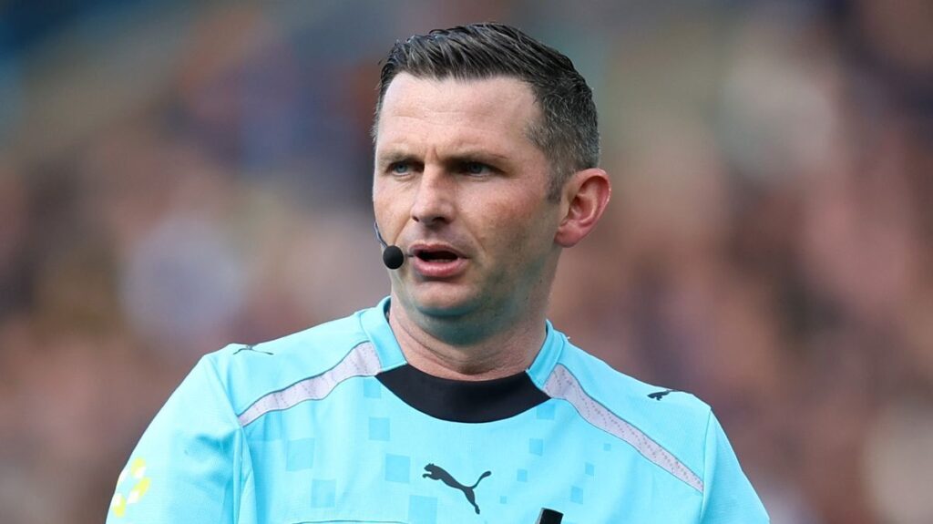 Premier League referee Michael Oliver looking closely at the pitch during a match