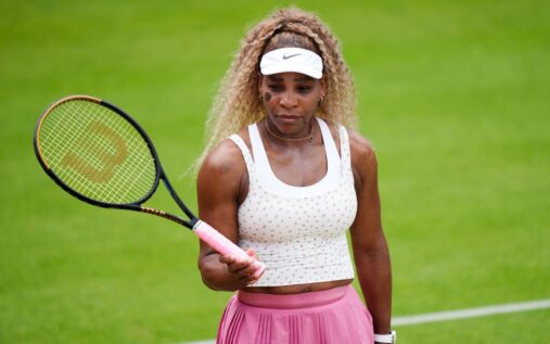 Serena Williams dressed in traditional white hitting a tennis ball on a grass practice court at Wimbledon
