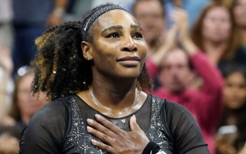 Serena Williams looking focused on a grass tennis court holding her racket
