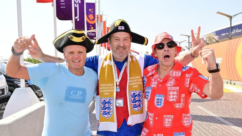 England football fans displaying flags and cheering in a crowded stadium