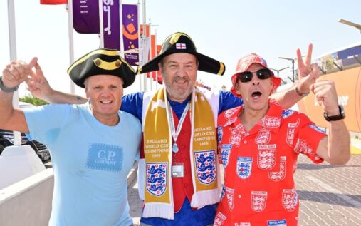 England football fans displaying flags and cheering in a crowded stadium