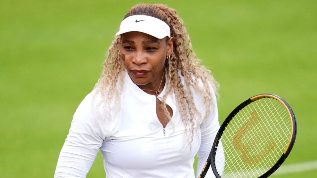Serena and Venus Williams smiling and celebrating together on a grass tennis court at Wimbledon