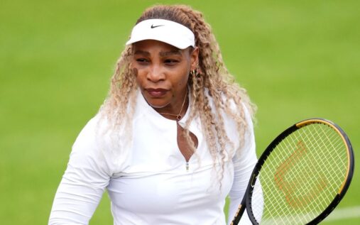 Serena and Venus Williams smiling and celebrating together on a grass tennis court at Wimbledon